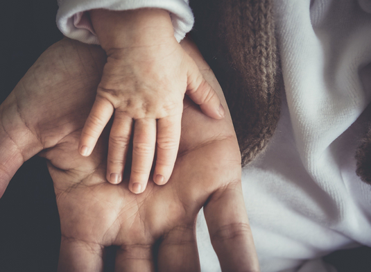 Baby hand laying on a dad's hand in a loving way.