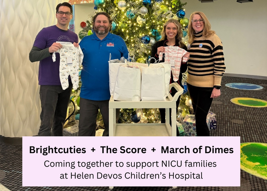 Four people standing in front of a decorated Christmas tree, holding baby sleepers with text about supporting NICU families.
