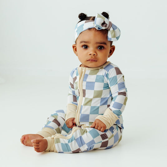 Baby wearing a checkered outfit and headband on a white background