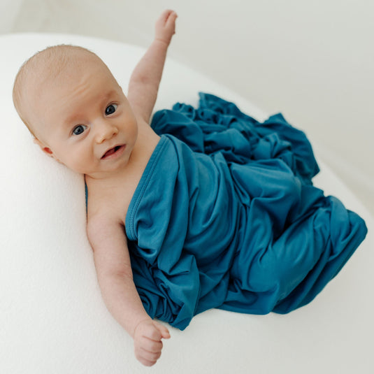 Baby stretching in on of our Blue Charcoal Stretchy Swaddle Blankets. A timeless baby essential, making it an excellent choice for Baby Shower Gifts.