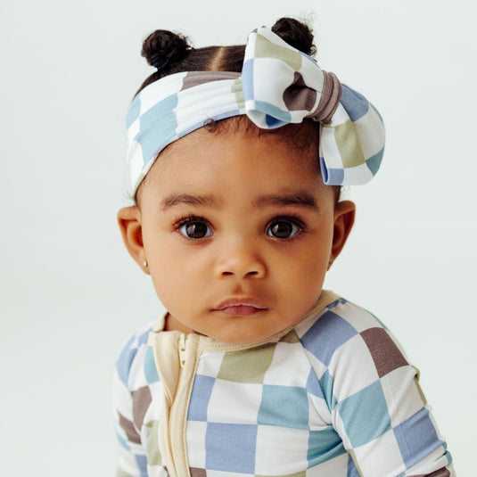 Baby in our Luxe Checker bamboo baby bows, a trendy accessory for newborns. The perfect complement to bamboo baby clothes and make chic baby shower gifts for new parents.