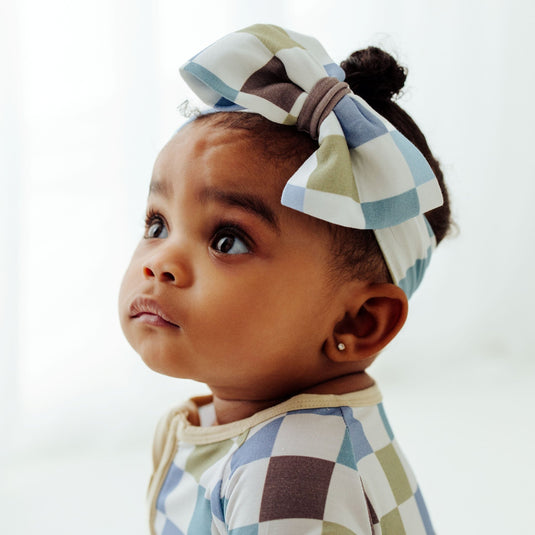 Baby looking up in our Luxe Checker bamboo baby bows, a trendy accessory for newborns. A must have to complement to bamboo baby clothes, plus they make for great baby shower gifts.