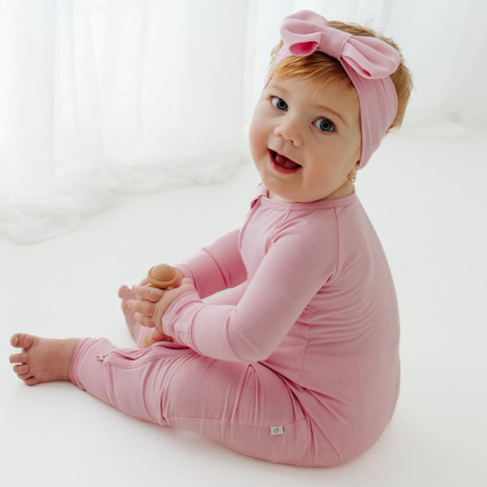 Happy baby looking up in Petal Glow bamboo bow headband – a stylish and ultra-soft accessory for newborns. A favorite to complement our bamboo baby clothes and a thoughtful baby shower gift.