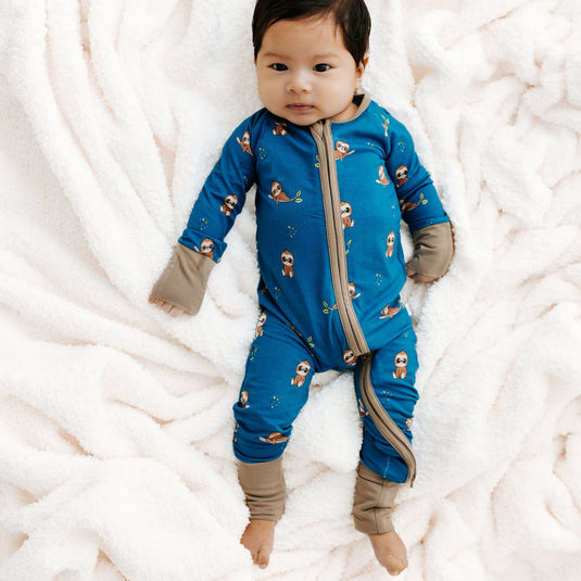 Baby laying in Sleepy Sloth bamboo baby pajamas, a cozy and hypoallergenic baby onesie made for sensitive skin. A must-have in bamboo baby clothes and for thoughtful baby shower gifts.