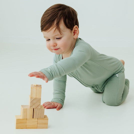 Baby playing in Frosted Sage bamboo baby sleeper – a breathable and ultra-soft sleeper designed for sensitive skin. Ourbaby sleepers area a top choice in bamboo baby clothes and a beautiful baby shower gift.
