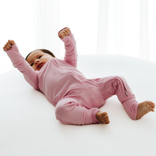 Baby stretching in Petal Glow bamboo baby sleeper – a soft, hypoallergenic sleeper designed for delicate skin. These baby sleepers are a must-have in bamboo baby clothes and a sweet baby shower gift.