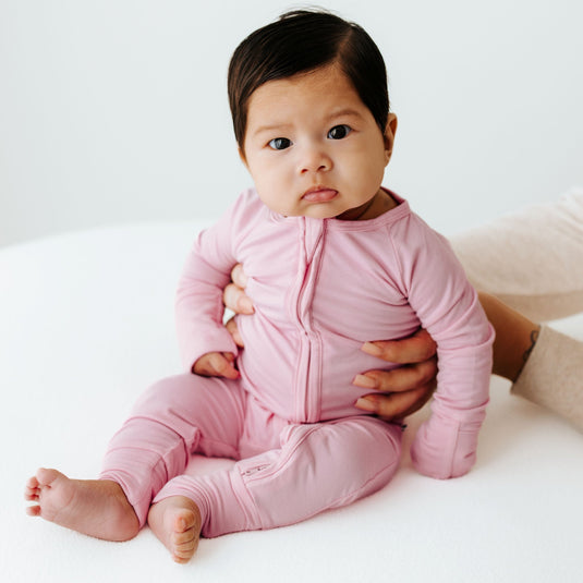 Baby in Petal Glow bamboo baby sleeper – a buttery-soft sleeper in delicate blush pink. These baby sleepers are a top pick in bamboo baby clothes and a heartfelt baby shower gift.