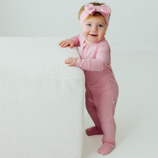 Baby standing in Petal Glow bamboo baby sleeper – a breathable, silky-smooth sleeper designed for all-night comfort. These baby sleepers are a top choice in bamboo baby clothes.