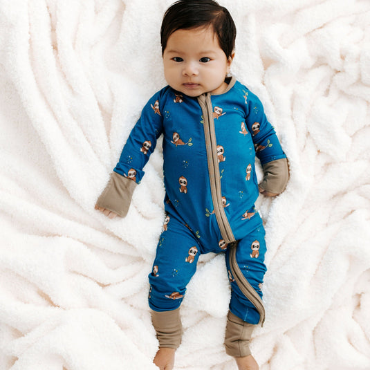 Baby wearing a blue onesie with patterns on a white textured surface