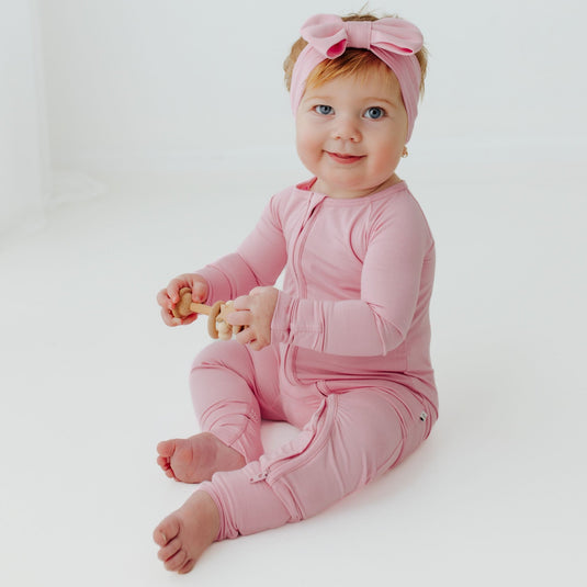 Baby sitting up in Petal Glow bamboo baby pajamas, our soft and breathable baby onesies designed for delicate skin. A must-have in bamboo baby clothes and for meaningful baby shower gifts.