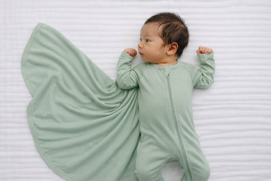 Newborn baby wearing sage preemie bamboo sleeper with matching swaddle for soft, gentle comfort