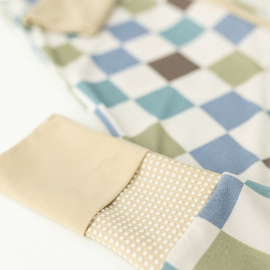 Close-up of a checkered fabric with beige, blue, and green patterns on a white background