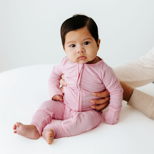 Baby sitting being held by mom hands