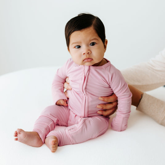 Baby in Petal Glow bamboo baby pajamas, a buttery-soft baby onesies in a delicate blush pink. A top pick in bamboo baby clothes and for heartfelt baby shower gifts.