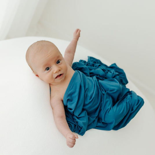 Baby stretching in on of our Blue Charcoal Stretchy Swaddle Blankets. A timeless baby essential, making it an excellent choice for Baby Shower Gifts.