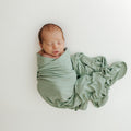 Baby sleeping in one of our Frosted Sage Stretchy Swaddle Blankets, wrapped in luxurious bamboo fabric for maximum comfort. A premium addition to bamboo baby clothes and great for Baby Shower Gifts.