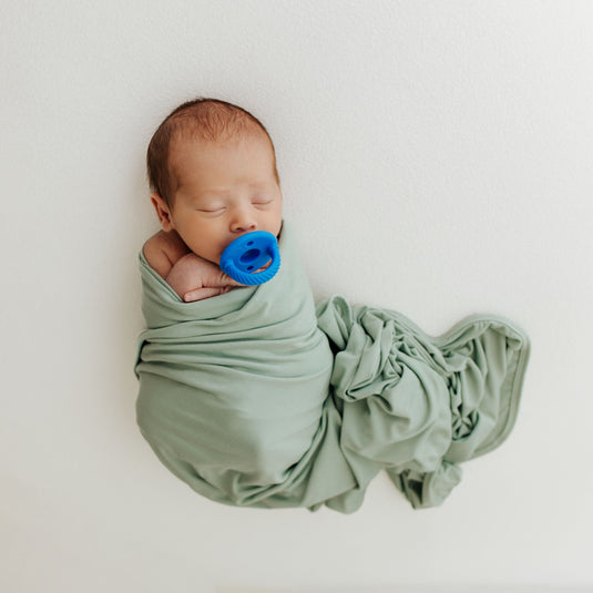 Frosted Sage | Baby snugly wrapped in one of our Frosted Sage Stretchy Swaddle Blankets. A must-have in bamboo baby clothes and for thoughtful Baby Shower Gifts.