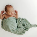 Baby napping soundly in one of our Frosted Sage Stretchy Swaddle Blankets, wrapped in luxurious bamboo fabric. A premium addition to bamboo baby clothes and great for Baby Shower Gifts.