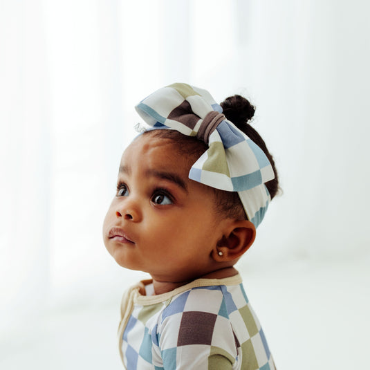 Baby looking up in our Luxe Checker bamboo baby bows, a trendy accessory for newborns. A must have to complement to bamboo baby clothes, plus they make for great baby shower gifts.