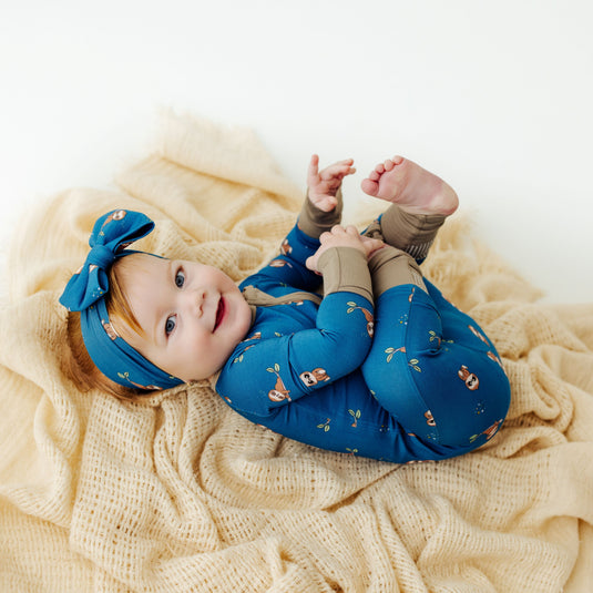 Baby wearing Sleepy Sloth bamboo baby bow – enjoying the ultra-soft and stretchy fabric. A cozy and hypoallergenic must-have in bamboo baby clothes and an elegant baby shower gift.