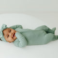 Baby in Frosted Sage bamboo baby pajamas, a muted green baby onesies designed for all-day comfort. A gender-neutral favorite in bamboo baby clothes and for thoughtful baby shower gifts.