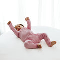 Baby stretching in Petal Glow bamboo baby sleeper – a soft, hypoallergenic sleeper designed for delicate skin. A must-have in bamboo baby clothes and a sweet baby shower gift.