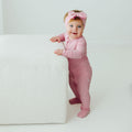 Baby standing in Petal Glow bamboo baby pajamas, a breathable and silky-smooth baby onesies designed for all-night comfort. A top choice in bamboo baby clothes and for thoughtful baby shower gifts.