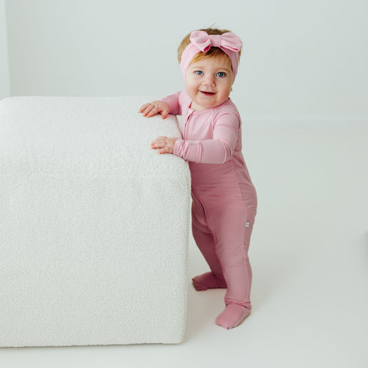 Baby standing in Petal Glow bamboo baby sleeper – a breathable, silky-smooth sleeper designed for all-night comfort. A top choice in bamboo baby clothes and a thoughtful baby shower gift.