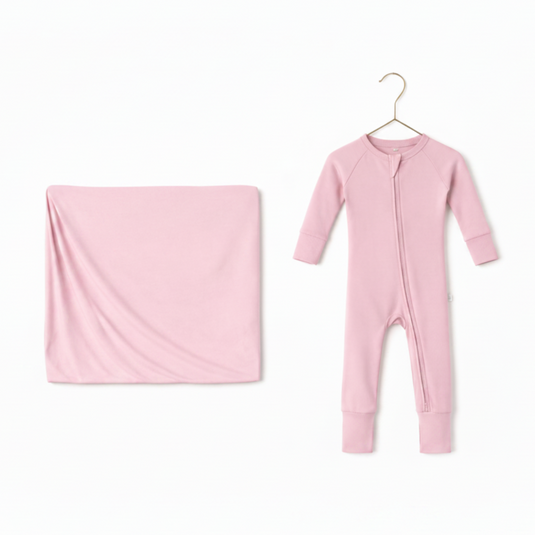 Pink baby onesie and blanket on a white background